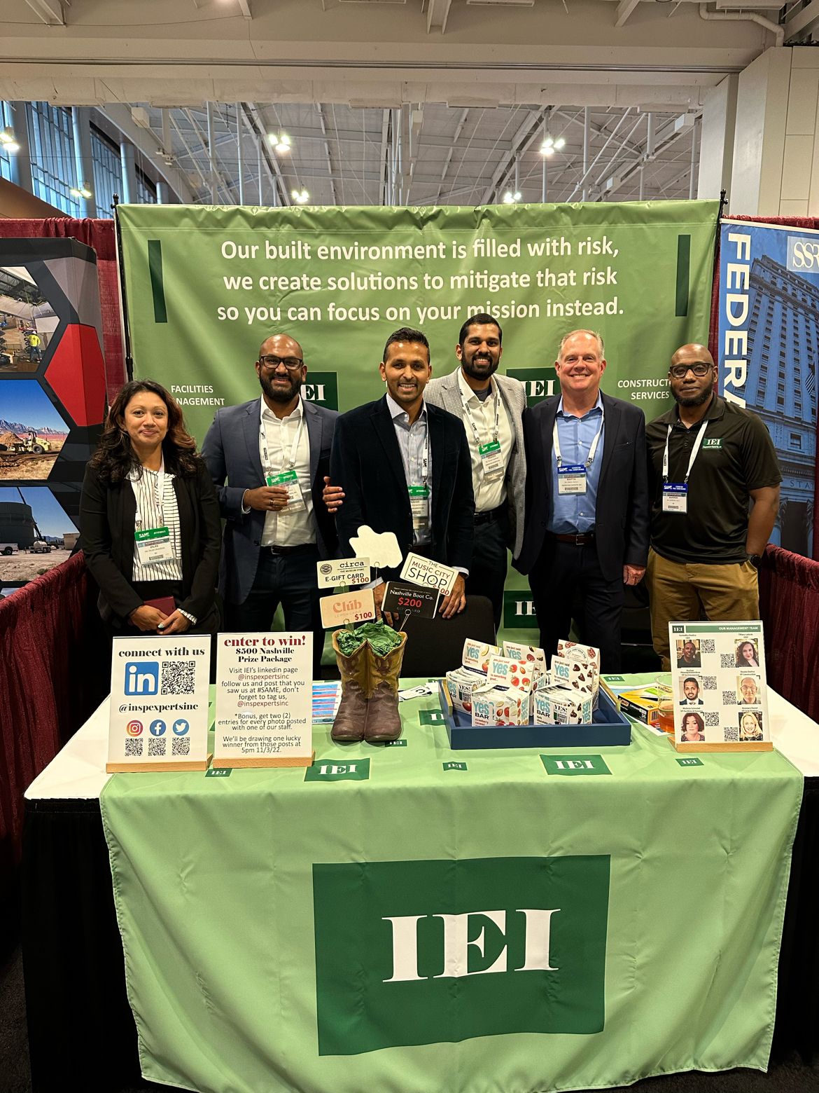 IEI team members standing together at the IEI exhibit booth at an industry conference