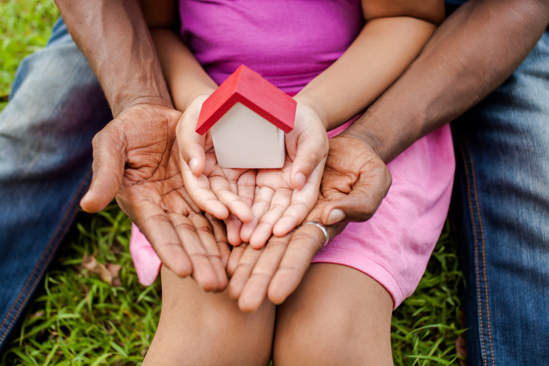 Family holding a small model house, representing safe and stable housing